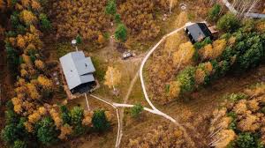 Aerial view of cottages connected by paths through autumn woodland